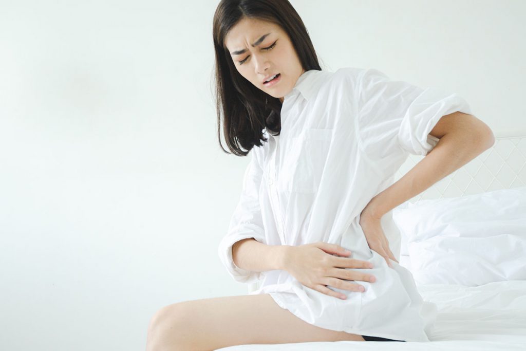 Women wear white shirt on the bed in a room with hip pain.